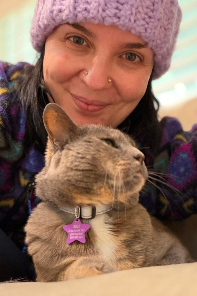 Woman with a gray tabby cat, both showing affection and companionship.